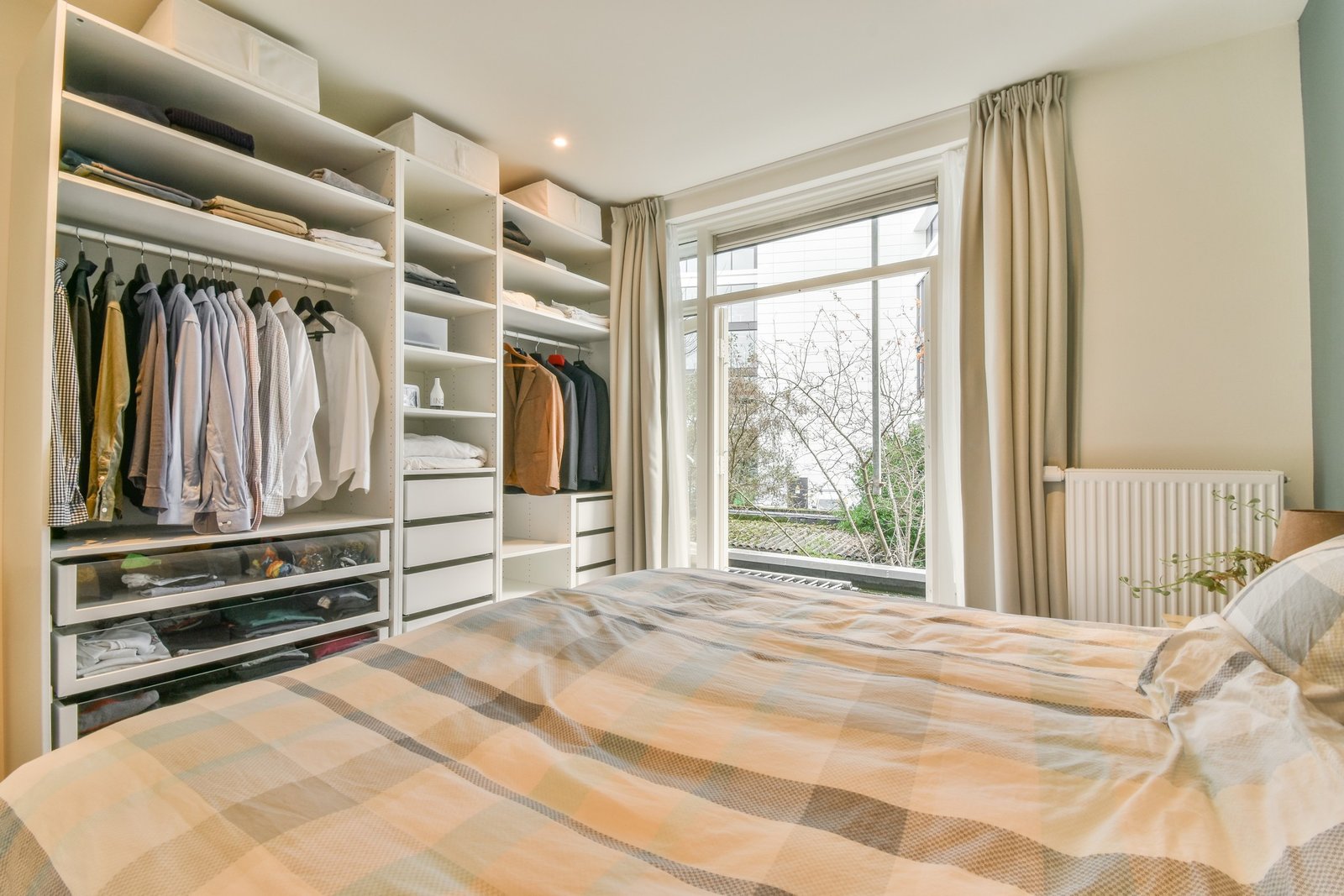 Offener Kleiderschrank im Schlafzimmer an einer Wand