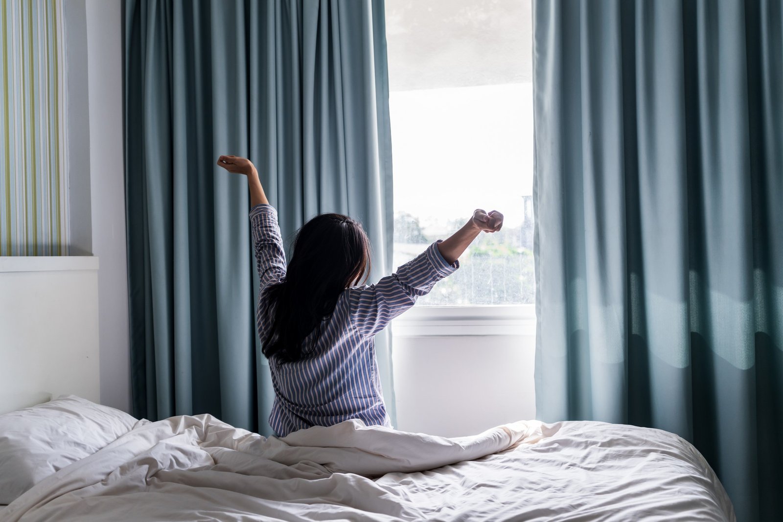 Person wacht morgens im Schlafzimmer auf